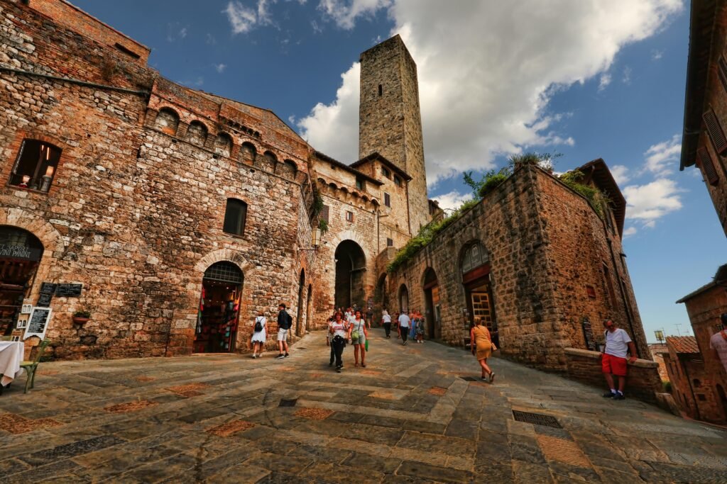 Tourists exploring the ancient Torre dei Becci in San Gimignano, Tuscany.