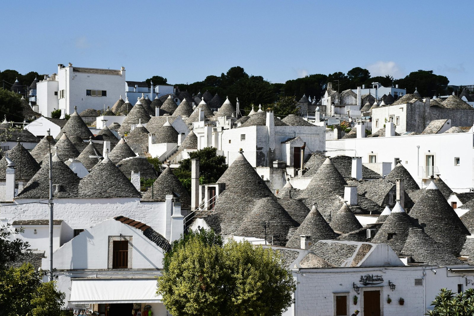 Explore the unique architecture of trulli houses in Apulia, Italy, under a clear blue sky.