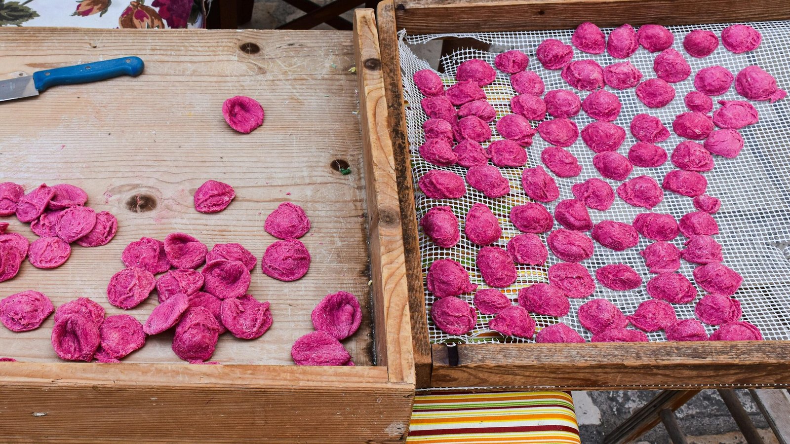 Freshly made beetroot orecchiette pasta drying outdoors in Apulia, Italy.